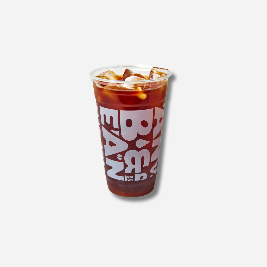 A tall clear plastic cup filled with iced coffee and ice, wrapped with large bold “BEAN & BEAN” lettering around the cup.
