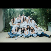 The Altieri family, dressed in white tops and jeans, smiling together while posing outdoors in front of tropical greenery.