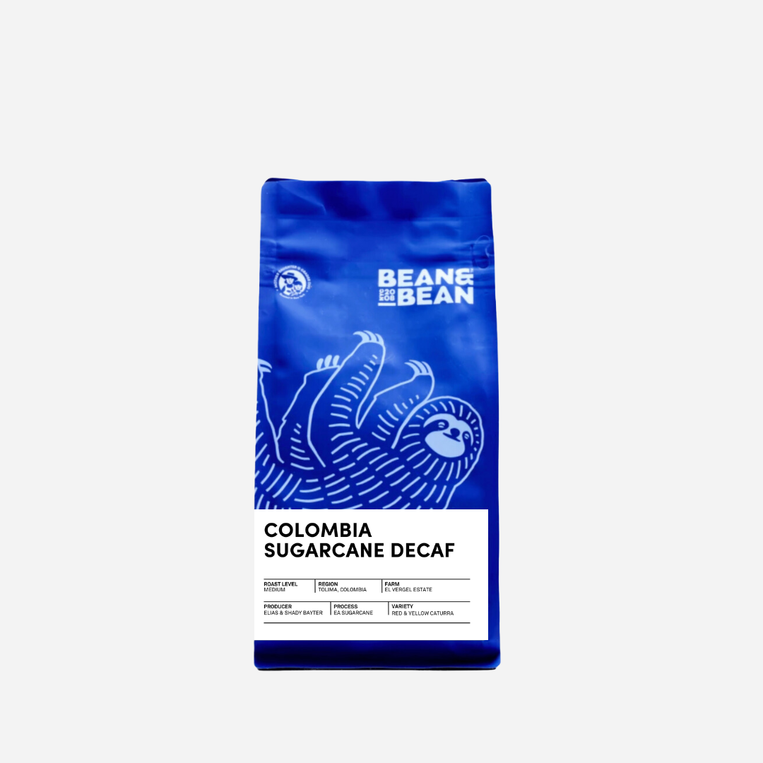 Purple "Bean & Bean Coffee Roasters" bag with a colored label that says Colombia Sugarcane Decaf