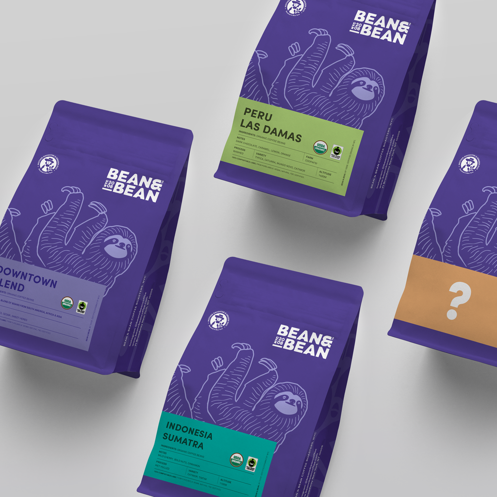 Four Purple "Bean and Bean Coffee" Bags, one with a purple label that says "Downtown Blend," another with a green label that says "Peru Las Damas", another with an orange label that has a question mark on it, and another with a turquoise label that says "Indonesia Sumatra""